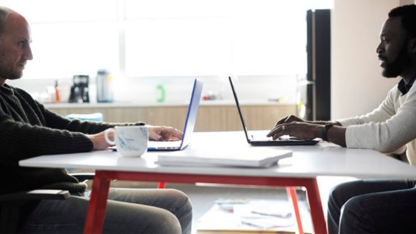 Two people sitting with computers